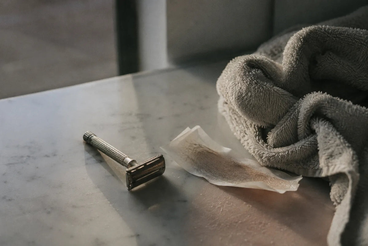 Rasoio, striscia di ceretta usata e asciugamano su un piano di marmo